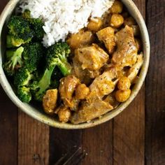 a bowl filled with rice, broccoli and chicken on top of a wooden table