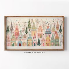 a painting hanging on the wall next to a wooden frame with trees and houses painted on it