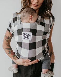 a woman holding a baby in a black and white checkerboard print wrapper