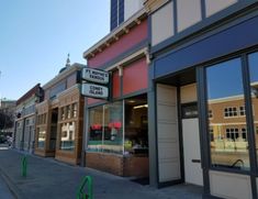 an empty street in front of a store with signs on the side of it's windows