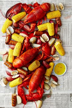 lobsters, corn on the cob and shellfish are laid out on newspaper