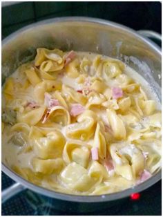 a pot filled with pasta and ham on top of a stove