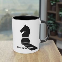 a black and white coffee mug sitting on top of a wooden table