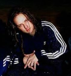 a man with dreadlocks sitting in a chair looking at the camera while holding his hand out