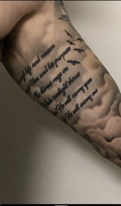 a man's arm with an ink quote on it and clouds in the background