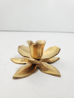 a gold flower shaped candle holder on a white surface