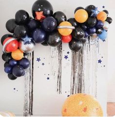 an arch made out of balloons with stars and planets hanging from the side on a wall