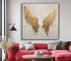 a living room with a red couch and a painting on the wall above it that has gold wings