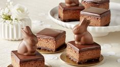 four pieces of cake with chocolate frosting and bunny ears on them sitting on plates