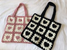 two crocheted purses sitting on top of a white bed next to each other