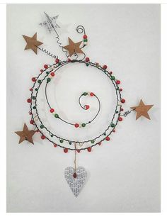 an art piece with stars and beads hanging from it's sides, on top of a white surface