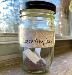 a jar filled with rocks and paper on top of a window sill