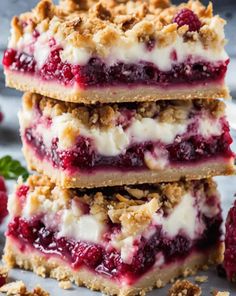 three raspberry crumble bars stacked on top of each other with fresh berries in the background