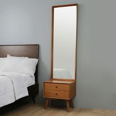 a bedroom with a bed, dresser and mirror in it's corner next to a nightstand