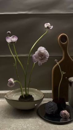 two vases with flowers in them sitting on a table next to a cup and saucer