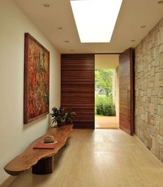 a wooden bench sitting in the middle of a hallway next to a wall with a skylight