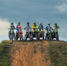 five people on dirt bikes are posing for a group photo at the top of a hill