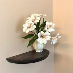 there is a vase with white flowers on the shelf next to the wall in the room