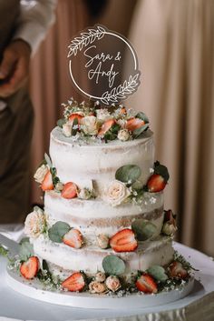 a wedding cake with fresh strawberries and greenery