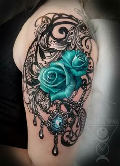 a woman's shoulder with a blue rose and ornate design on the back of her arm