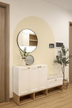 a living room with white furniture and a round mirror on the wall