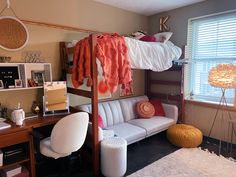 a bedroom with bunk beds and a couch in the corner next to a window,