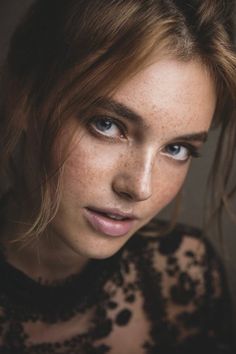 a woman with freckled hair and blue eyes looks at the camera while posing for a photo