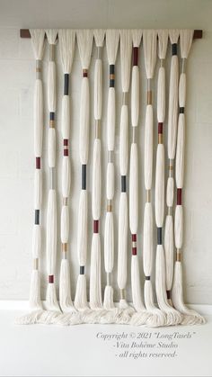 an art piece made out of white yarn and wooden dows, hanging on a wall