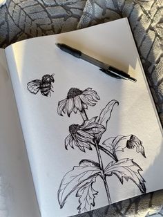 a drawing of a sunflower with two bees on it next to a fountain pen