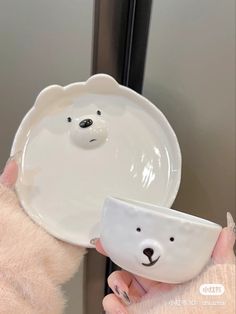 a person holding a white plate with a bear face on it and a bowl in the shape of a polar bear