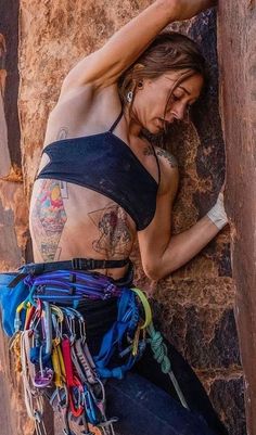 a woman climbing up the side of a rock with her hands on her hips and arms behind her head