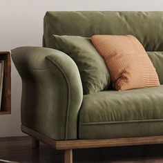 a green couch sitting on top of a hard wood floor next to a book shelf