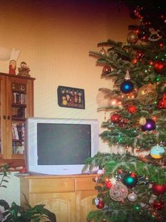 a christmas tree with ornaments in front of a television