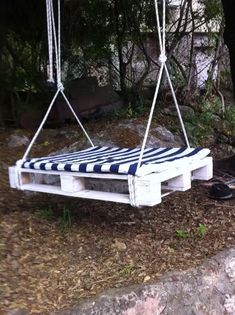 a white and blue striped swing bed in the woods