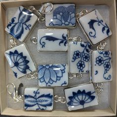 blue and white tiles in a box with silver chain hanging from it's sides