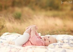 a baby laying on top of a bed in a field