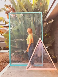 a woman standing in front of a blue and pink structure with two triangles on it