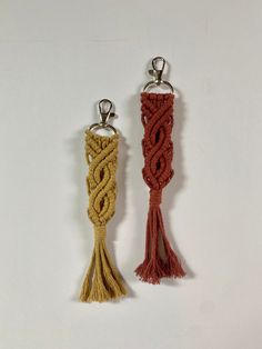 two tasseled keychains are shown on a white surface