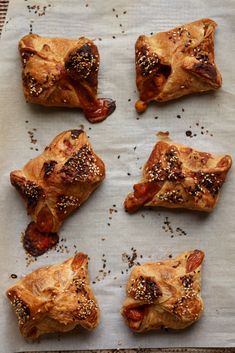 six pastries on a baking sheet covered in pepperoni and other toppings, ready to go into the oven