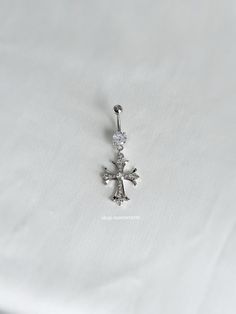 a silver cross pendant on a white cloth