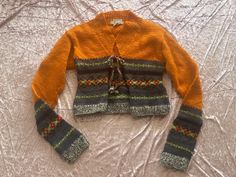 an orange cardigan sweater on a bed