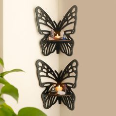 two butterfly shaped candle holders on the wall