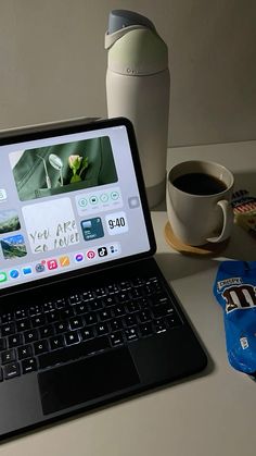 an open laptop computer sitting on top of a desk next to a cup of coffee