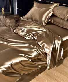 an unmade bed with gold sheets and pillows