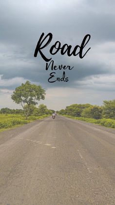 the road never ends with a motorcycle driving down it and trees in the distance on either side