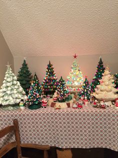 a table with christmas trees on it and other decorations in the room next to it