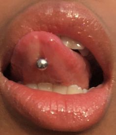 a close up of a person's tongue with a piercing on it