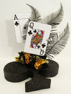 two playing cards sitting on top of black rocks next to a palm tree and fern