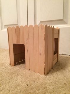 a dog house made out of wooden boards on the floor in front of a door