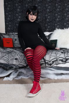 a woman sitting on top of a bed wearing red and black striped stockings